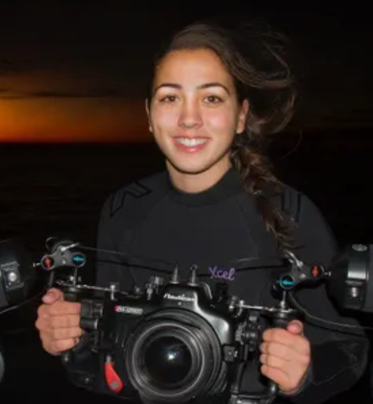 Photo of Lauren Remeiro holding camera rig, dusk/dawn in the background